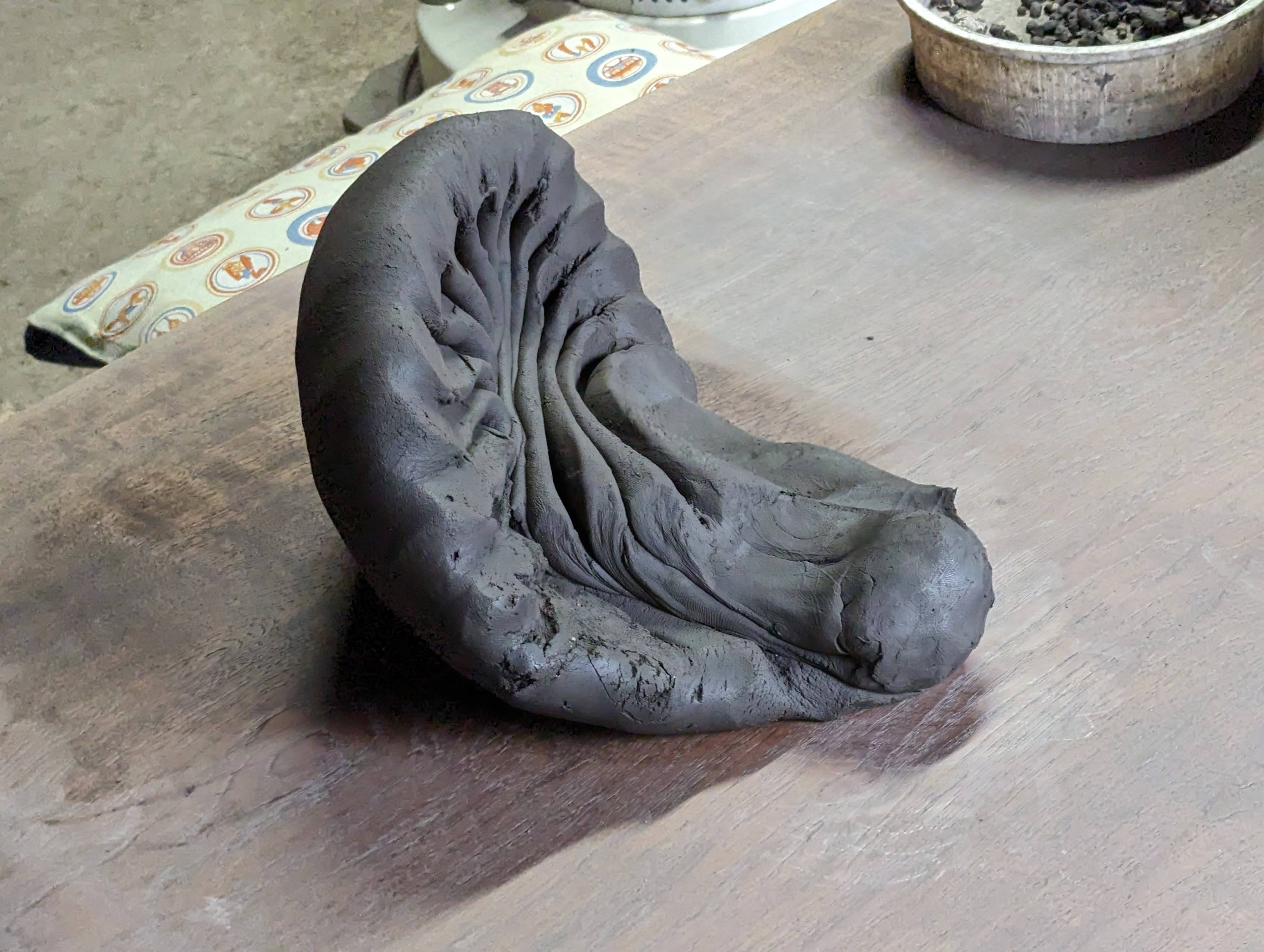 A rounded lump of clay kneaded into a folded, almost floral pattern